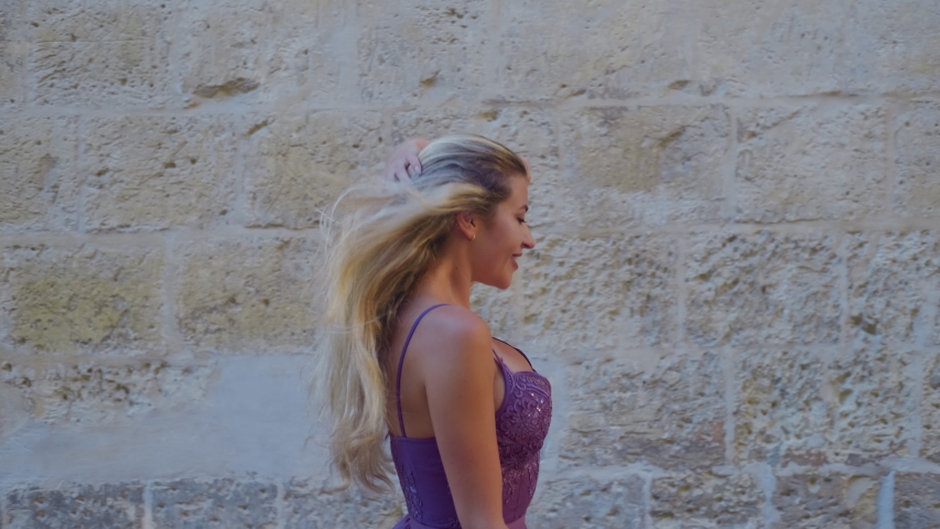 Sexy blonde woman in a dress walks in the square in the old city