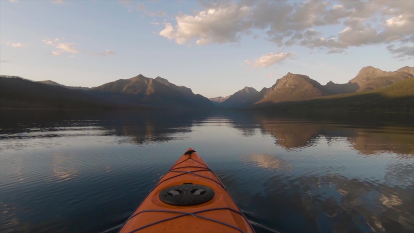 Kayaking in Lake McDonald during a sunny summer sunset with American Rocky Mountains in the background. Taken in Glacier National Park, Montana, USA. 4k Footage Royalty-Free Stock Footage #1040553515