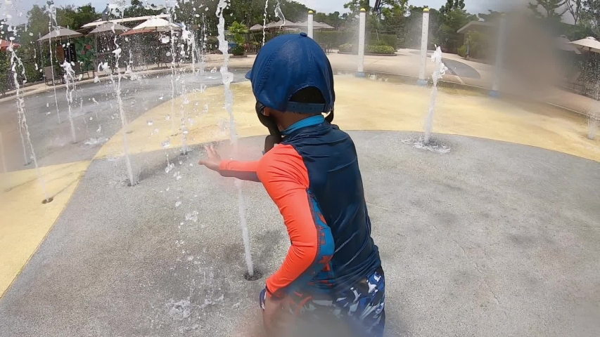 Little boy is running through the water tunnel in water aqua park playground.