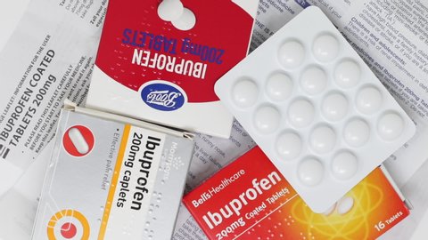London / UK - November 7th 2019 - Ibuprofen packets of medication - supermarket own brands, blister packs and instruction leaflets rotating on a table, view from above