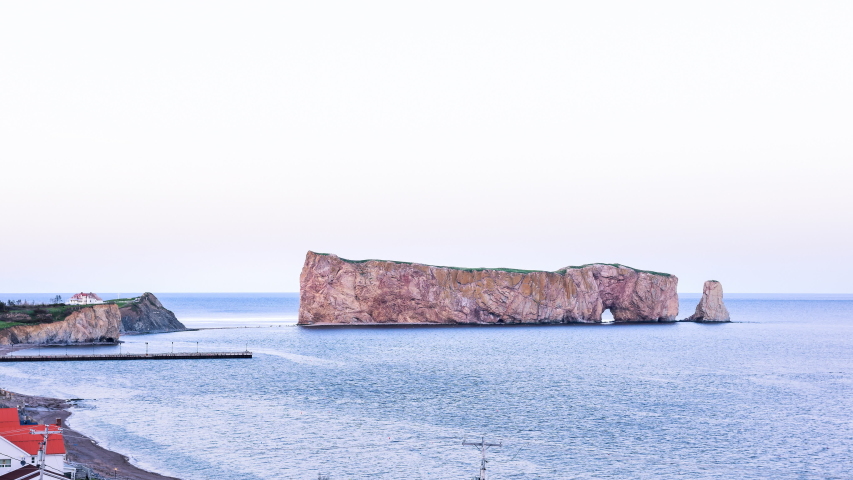 Timelapse of Rocher Perce rock sunset purple twilight in Gaspe Peninsula, Quebec, Gaspesie region, Canada, Saint Lawrence gulf water waves cinemagraph loop of famous arch