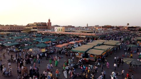 Marrakech, Morocco - 16 July 2019: Motion lapse with walking crowd of people at famous city square Jamaa el Fna (Jemaa el-Fna) in the evening.
