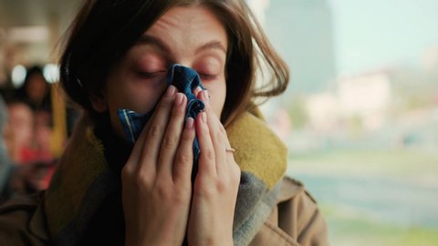 Woman blowing her nose into handkerchief on the tram on a cold autumn day at the start of the flu season disease fever flu grippe health illness infection influenza migraine sickness slow motion