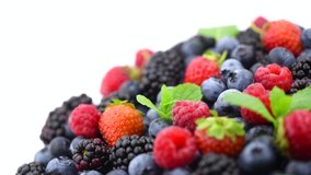 Berries. Various colorful berries rotation background. Mint leaves, Strawberry, Raspberry, Blackberry, Blueberry close-up rotating backdrop, isolated on white. Bio Fruits, Healthy eating, diet. 4K UHD