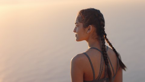 woman on mountain top looking at calm view of ocean at sunset girl standing on edge of cliff enjoying travel freedom