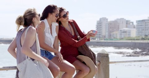 Teenage girls taking selfie at beach on summer vacation wearing sunglasses close up