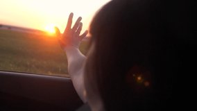 road travel trip concept. girl waving her hand in the window sunlight the wind In car slow motion video. lifestyle brunette girl put her hand out the window sunset sunlight