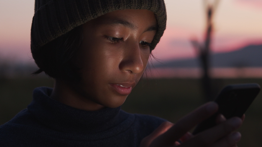 Close up shot of asian little girl using smart phone smiling and expression on her face in the sunset 