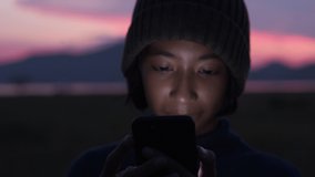 Close up shot of asian little girl using smart phone smiling and expression on her face in the sunset 