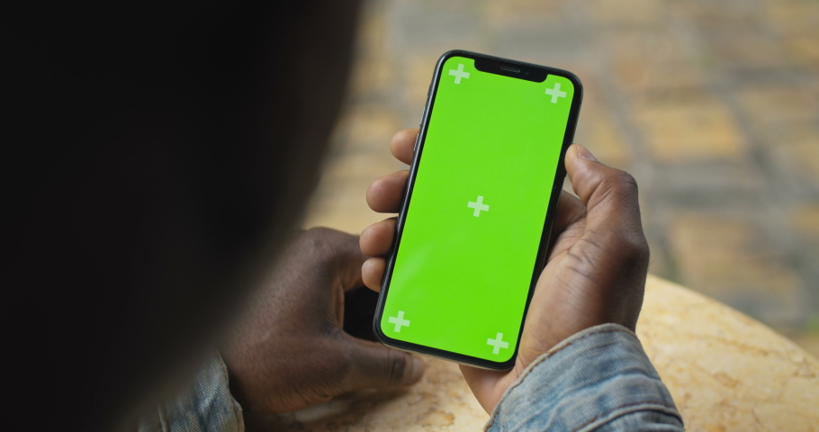 Close Up Shot of Head and Hand of Afro American Man Holding his Smartphone with Green Screen and Looking on it, Scrolling, Touching Screen. Backside View. Mock up Royalty-Free Stock Footage #1040607584
