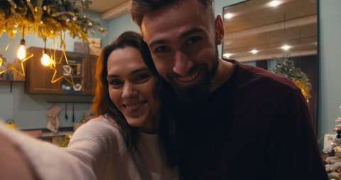 Phone camera POV Caucasian couple or family having a video call with friends or family during Christmas holidays. 4K UHD RAW graded footage