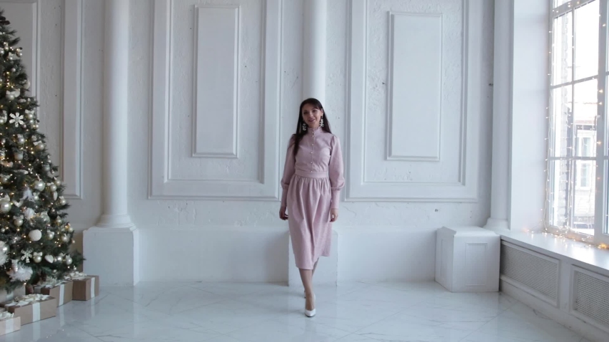 The girl goes near the Christmas tree at home. Beautiful sexy girl next to the Christmas tree. Brunette posing next to the Christmas tree. Christmas tree. Slow mo