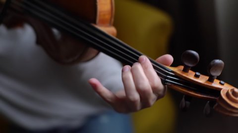 Woman violin musician playing at home, close-up in slow motion. Lovely young woman is practicing playing musical instrument at home.