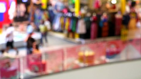 Blurred tourists walking in department stores and fashion clothes shops in shopping mall