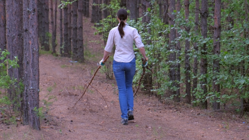 Young woman brunette carries felled trees to a forest scout