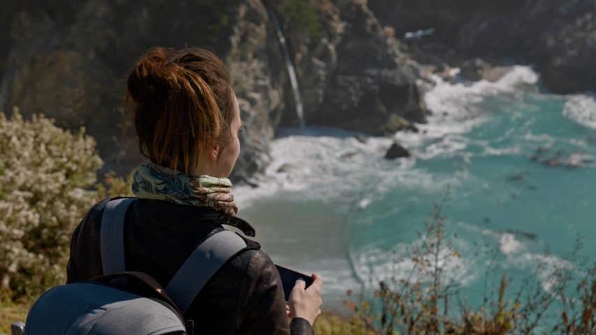Woman filming McWay Falls in Julia Pfeiffer Burns State Park, USA