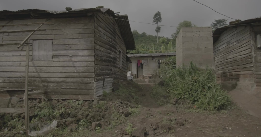 Stationary shot of path behind wooden house. The ground surrounding the house is uneven. Ungraded footage, shot on Arri Amira with Zeiss CP2 lenses. Filmed in slow motion.