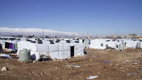 January 2017 - Beqaa Governorate, Lebanon: Pan right on Syrian refugee camp. Snow on moutains in back