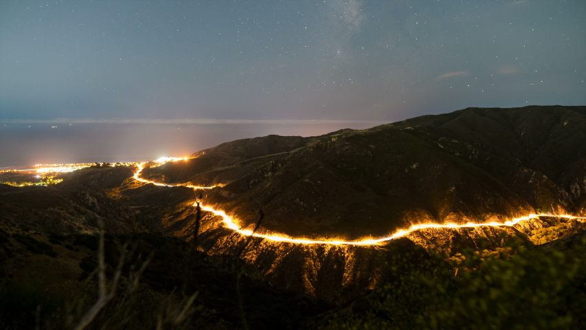 Astro timelapse tracking shot of Milky Way galaxy over highway in Malibu, California