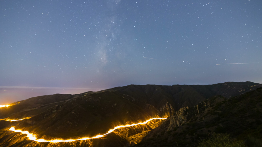 Astro timelapse of Milky Way galaxy over highway in Malibu, California