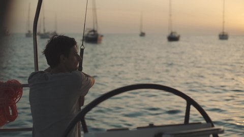 Man on a yacht enjoys sunset on Cala Saona bay. Luxury yacht near the Formentera island. Slow motion