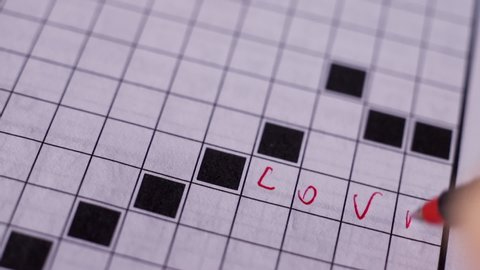 Playing crosswords ,writing the word love with red marker , macro lens