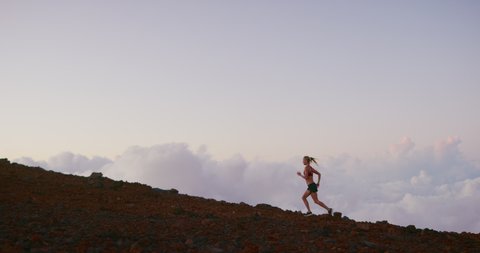 Strong independent woman running up a mountain in the clouds with strength and determination, runner achieving her ultra marathon goals outdoors