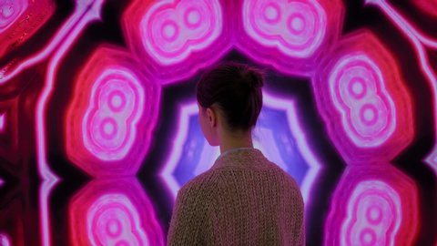 MOSCOW, RUSSIA - JUNE 01, 2019: Woman standing in front of large interactive display with colorful abstact video at modern immersive exhibition. Education, digital art and entertainment concept