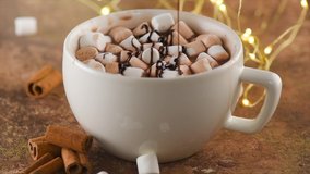 Hot Chocolate with Marshmallow. Chocolate topping pouring in a Cup of Hot beverage, closeup. Concept of winter time, fall, Christmas holidays. 4K UHD video, slow motion