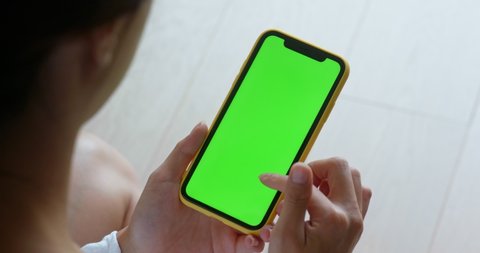 Woman use of mobile phone with green screen at home
