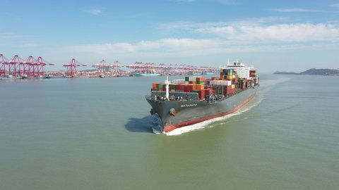 SHANGHAI, CHINA – SEPTEMBER 2019: Drone flight of large container ship sailing gently into the deep-water Port of Shanghai, international shipping and maritime transport in China