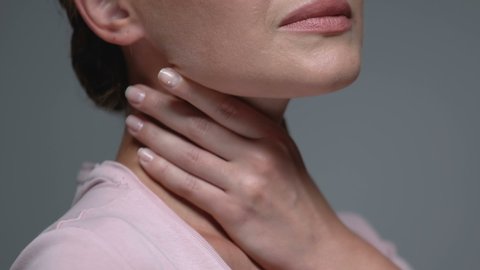 Woman holding throat against grey background.angina health problem, virus.