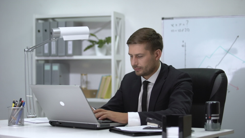 Male boss finishing work on laptop and standing up then feeling strong pain in back. Royalty-Free Stock Footage #1040687426