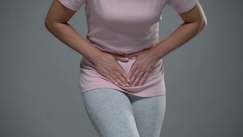 Woman writhing from pain in lower abdomen. menstrual pain, risk of miscarriage