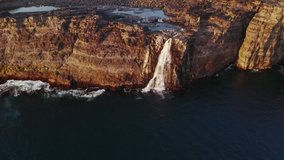 Aerial drone video flying over Bosdalafossur waterfall on Sorvagsvatn lake in sunset time. Vagar island, Faroe Islands, Denmark. UHD 4k video
