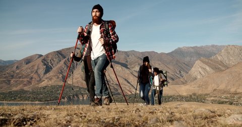 Group of four hipster friends travelling together, hiking and adventuring in mountains. Students on vacation - friendship, travel destination concept 4k footage