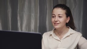 Qualified and successful young caucasian woman using laptop computer and making online video call. Female freelancer working in work space at home, talking with client and smiling nice