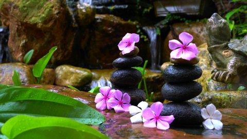 Stack of zen stones or pebbles next to garden waterfall. Zen or beauty and wellness concept.