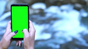 technology in nature concept: smartphone with green screen waterfall cascade background chromakey tracking matte vfx ready shot natural organic sport challenge abstract 4k