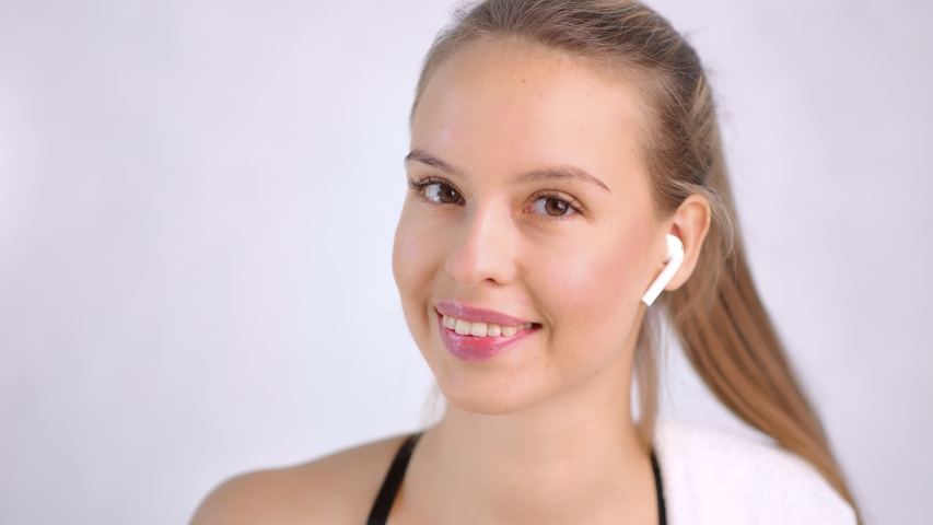 Closeup pretty fit lady with beauty skin wearing headphones isolated at light studio background | Shutterstock HD Video #1040706848