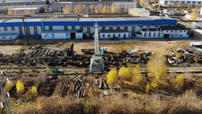 Aerial flight over an industrial warehouse for the recycling and disposal of old scrap metal. A large crane on rails loads pieces of metal pile into a truck. Aerial shot taken by drone - Powered by Shutterstock - Get 15% off with code: PIKWIZARD15