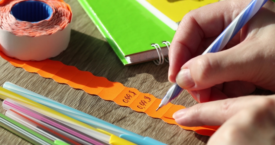 A female seller writes a price tag on a product price of 0.99 cents