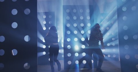 4K Professional Hip Hop , freestyle or swag dancers . Stylish young couple dancing crazy modern dance near decorative walls with many circle holes and spotlight . Shot on RED HELIUM Cinema Camera .