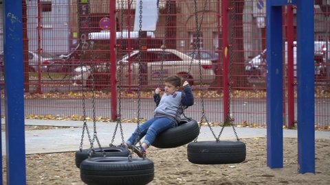 October 20, 2019. Germany. Dusseldorf. excited boy outdoors swinging on tire at playground. Young boy sitting on tire swing set on playground. Children playing outdoors.