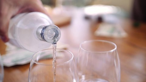 shooting close up pour water from a decanter into a small glass glass