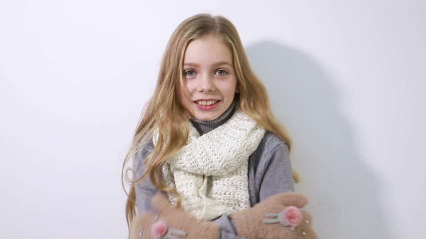 Little girl in winter gloves, winter clothes, preparing for winter