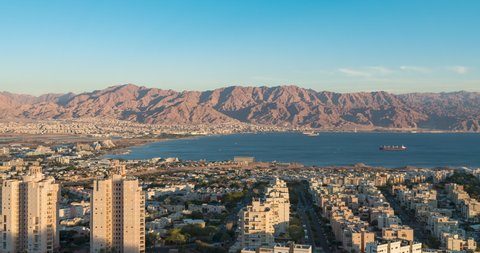 Panoramic aerial Timelapse view of eilat coastline at evening, with Ships anchoring at the red sea, israel. At the distance is the city of Aqaba, Jordan and the moav mountains