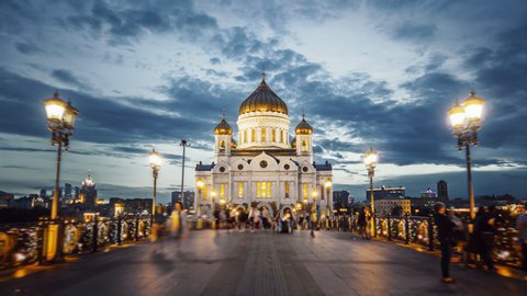 Amazing hyperlapse of the Cathedral of Christ the Saviour in Moscow on the evening. Camera moving along the beautiful bridge towards the church all in glittering lights, night city on the background.