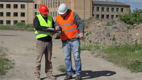 Construction employees with documents near building