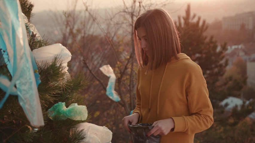 Volunteer young woman collects trash in the trash bag dirty ecosystem lifestyle garbage recycling clean eco picking environment pollution recycle rubbish trash bag close up slow motion